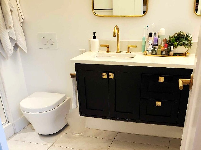 A spotless bathroom with a navy vanity and white tile floor