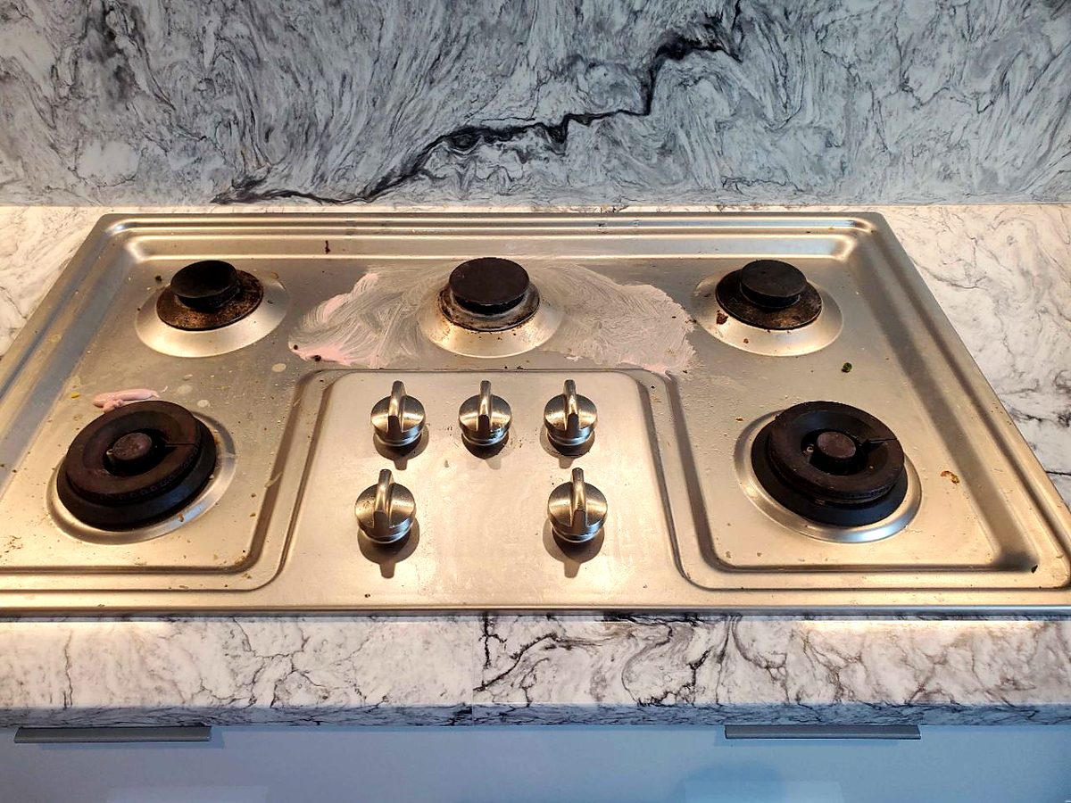 Stovetop before cleaning, with grease stains and residue around the burners